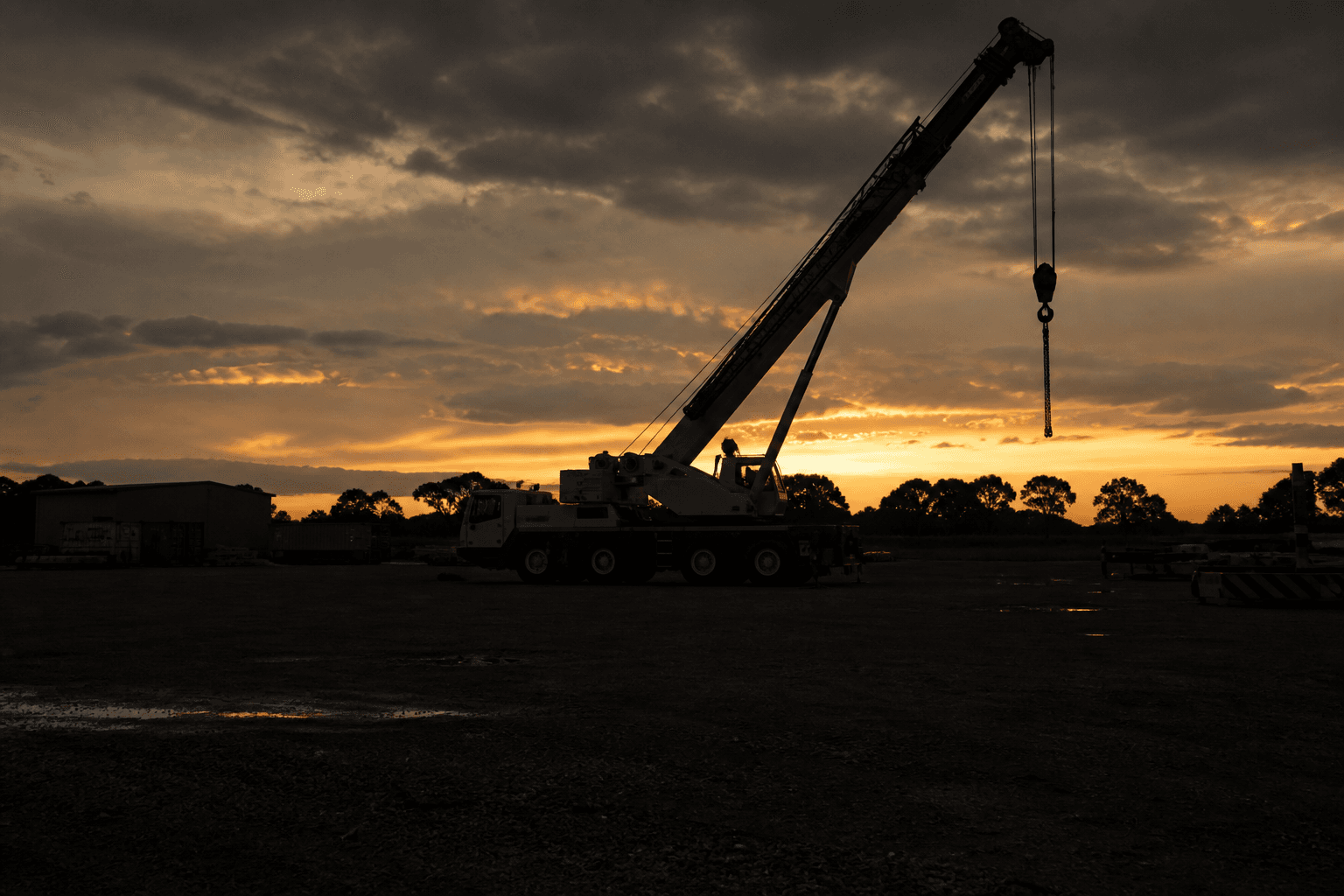 A mobile crane in a rural yard at dusk.